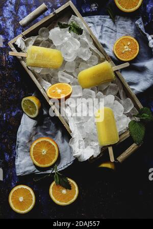 Draufsicht auf orangefarbene Eiszapfen auf einer gefüllten Holzkiste Mit Eiswürfeln Stockfoto