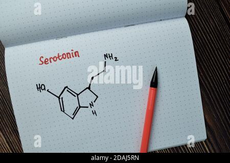 Chemisches molekulares Formule Hormon Serotonin schreiben auf einem Buch isoliert auf Holztisch. Stockfoto