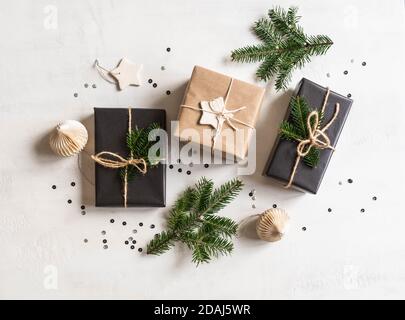 Flach Lay von Weihnachtsgeschenken nachhaltig verpackt. Weihnachtsverpackung in natürlichen und schwarzen Farben auf weißem Texturhintergrund. Draufsicht. Stockfoto