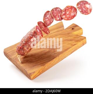 Geschnittene Salami fliegen auf einem hölzernen Schneidebrett isoliert Stockfoto
