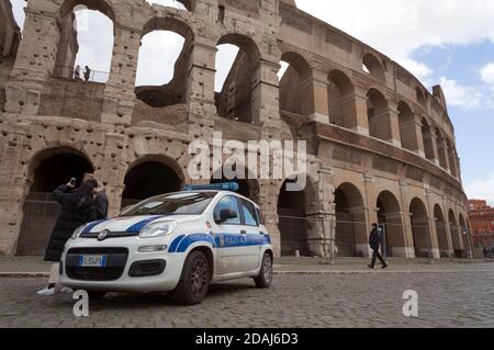 Ein Polizeiwagen steht vor dem Amphitheater Kolosseum (Baujahre 72-80), Denkmäler des antiken Rom mit Touristen in der Nähe. Stockfoto