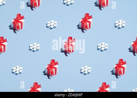 Weihnachtsmuster aus Geschenkschachteln und Schneeflocken auf blauem Hintergrund. Weihnachten, Winterferien, Neujahrskonzept. Minimalistischer Stil. Stockfoto