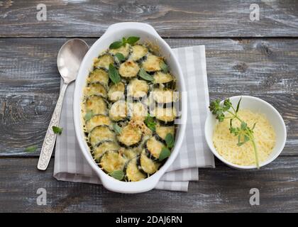 Gratin Zucchini mit Käse und Gemüse auf einem hölzernen Hintergrund. Leckeres hausgemachtes Essen Stockfoto