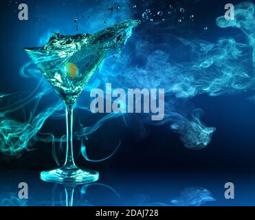 martini Cocktail spritzt auf dunkelblauem rauchigem Hintergrund Stockfoto
