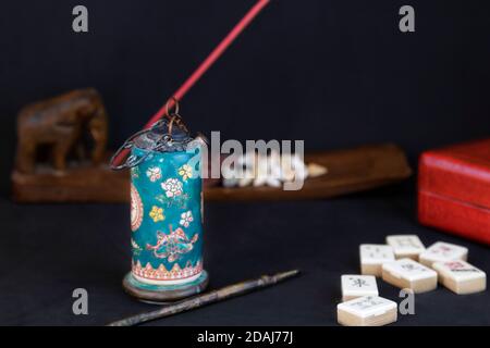 Antike Opiumpfeife und andere chinesische Gegenstände (Mahjong, Räucherstäbchen und eine rote Schachtel) vor schwarzem Hintergrund Stockfoto