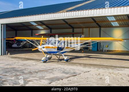 Gelbes und blaues ultraleichtes Flugzeug im Hangar Stockfoto