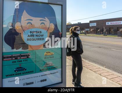 Eine Frau, die während der Coronavirus-Zeit in Toronto, Kanada, auf einen TTC-Bus wartet. Stockfoto