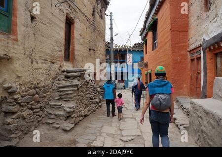 Einheimische und Touristen gehen entlang einer engen Gasse durch die Altstadt. Wanderung im geschlossenen Bereich des oberen Mustang. Nepal. Stockfoto