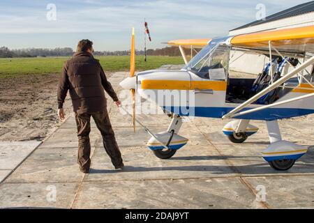 Pilot zieht ultraleichtes Flugzeug aus dem Hangar Stockfoto