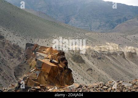 Ein großes Stück Fels liegt vor der Kulisse der Himalaya-Berge in der Region Mustang in Nepal. Stockfoto