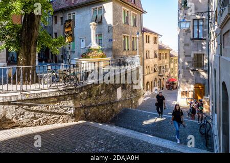 Die Menschen gehen die Rue du Perron hinauf, eine schmale steile Straße, die zum oberen Teil der Genfer Altstadt führt, die auf einem Hügel liegt. Stockfoto