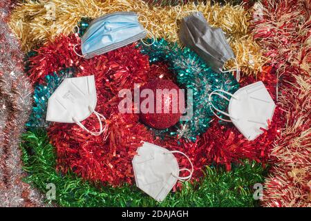 Overhead-Ansicht der Weihnachtsdekoration mit mehreren Anti-Virus-Gesichtsmasken auf der Oberseite. Persönliche Schutzausrüstung auf Partys Weihnachten. Stockfoto