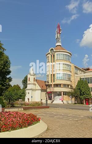 Kleine bescheidene evangelische Kirche neben einem zylindrischen modernen Apartmentgebäude in Alba Iulia, Rumänien. Stockfoto