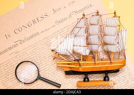 Schiff aus Holz und Stoff auf dem Hintergrund handgefertigt Eines Ausschnitts aus einer Kopie des Dokuments von 1776 über die Unterzeichnung der Unabhängigkeit von Stockfoto