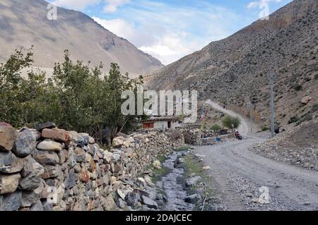 Eine unbefestigte Straße verläuft entlang eines Steinzauns im Himalaya, auf dem Weg nach Upper Mustang in Nepal. Stockfoto