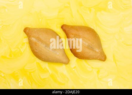 Blick von oben auf zwei frisch gebackene Bolillo Brötchen Seite an Seite auf einem gelb gestrichenen Hintergrund. Stockfoto