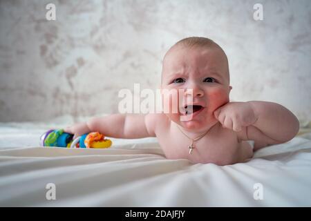 Nahaufnahme eines Babys mit Hautallergie auf dem Bett. Nahaufnahme des Gesichts eines Babys mit Hautallergie. Das Baby weint Stockfoto