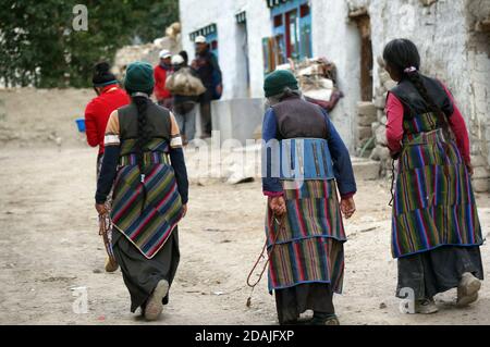 Drei nicht identifizierte nepalesische Frauen in traditioneller Nationalkleidung gehen die Straße hinunter in der Stadt Lo Mantang, der Hauptstadt des Oberen Mustang. Nepal Stockfoto