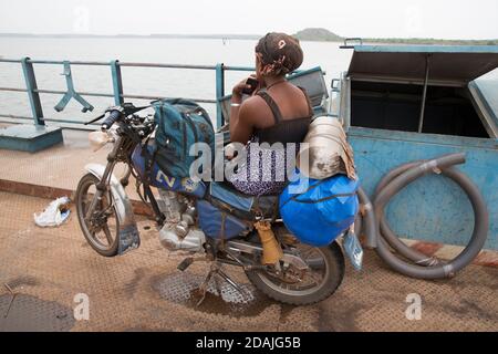 Selingue, Mali, 27. April 2015; EINE Passagierin auf ihrem Motorrad. Stockfoto