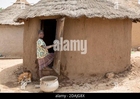 Delaba Koro, Dorf 60 km von Selingue, Mali, 27. April 2015; in diesem Dorf wurden viele Menschen vom Staudamm vertrieben. Ein Mädchen im Dorrway eines Hauses, dessen Lehmwand sie vor den Regenfällen repariert. Stockfoto