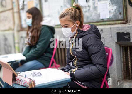 TURIN, ITALIEN - 13. November 2020: Zwei Schüler der Realschule Calvino, genannt Anita (R) und Lisa, folgen einem Fernunterricht (Dad) auf der Straße vor ihrer Schule, um gegen die Schließung von Schulen durch die Regierung aufgrund einer Zunahme der COVID-19 Coronavirus-Infektionen verhängt zu protestieren. Anita protestiert jeden Schultag seit dem 6. November, als Piemont zu einer roten Zone wurde, einen Tag später kam Lisa zu ihr. Am 11. November erhielt Anita einen Solidaritätsaufruf von der italienischen Bildungsministerin Lucia Azzolina. (Foto von Nicol Stockfoto