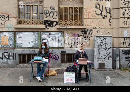 TURIN, ITALIEN - 13. November 2020: Zwei Schüler der Realschule Calvino, genannt Anita (R) und Lisa, folgen einem Fernunterricht (Dad) auf der Straße vor ihrer Schule, um gegen die Schließung von Schulen durch die Regierung aufgrund einer Zunahme der COVID-19 Coronavirus-Infektionen verhängt zu protestieren. Anita protestiert jeden Schultag seit dem 6. November, als Piemont zu einer roten Zone wurde, einen Tag später kam Lisa zu ihr. Am 11. November erhielt Anita einen Solidaritätsaufruf von der italienischen Bildungsministerin Lucia Azzolina. (Foto von Nicol Stockfoto