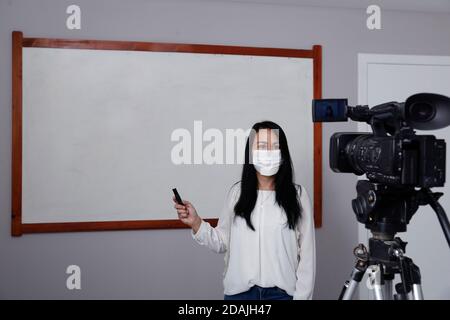 Lehrer mit Atemschutzmaske während der Präsentation von Online-virtuellen Klasse Stockfoto