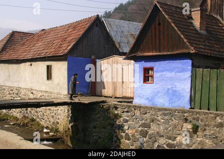 Sibiu County, Rumänien. Ältere Frau, die eine kleine Brücke im Dorf überquert. Stockfoto