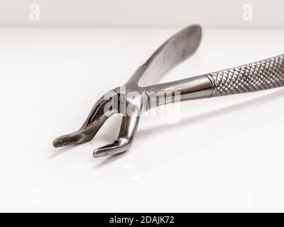 Metallzahninstrumente für die Zahnbehandlung auf weißem Hintergrund. Zahnzangen aus Edelstahl. Nahaufnahme. Geringe Schärfentiefe. Stockfoto