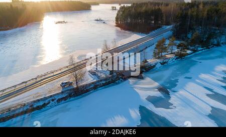 Luftaufnahme von Autobahn Damm und Auto bei Layby an Timosensalmi Meerenge zwischen gefrorenen Seen Pohjois-Konnevesi und Etelä-Konnevesi im Winter, Finnland Stockfoto