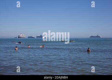 Schwimmer im Meer mit Kreuzfahrtschiffen hinter Overcombe, Dorset in Großbritannien, aufgenommen am 3. August 2020 Stockfoto