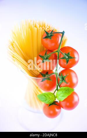 Tomate, Basilikum, Vegan Diät Lebensmittel, kreative Kirschtomate Zusammensetzung isoliert auf weiß. Frisches Basilikum, Tomaten, Kochkonzept, Draufsicht, Glas, Schüssel Stockfoto