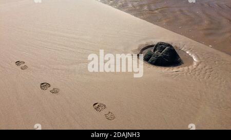 Spuren von Schuhen an der sandigen Küste in der Nähe des Flusses, nasser Sand, sandiger Fluss Stockfoto