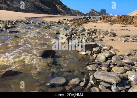 Kleiner Fluss fließt in den Ozean, schneller Strom fließt zum Meer, schöne Landschaft, erstaunliche Felsen Stockfoto