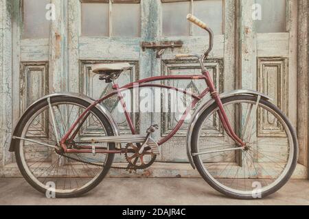 Vintage Beach Cruiser Fahrrad vor antiken Holz verwittert Türen Stockfoto