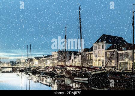 Abendansicht eines holländischen Kanals mit Segelbooten während Schneefall im Stadtzentrum von Zwolle Stockfoto