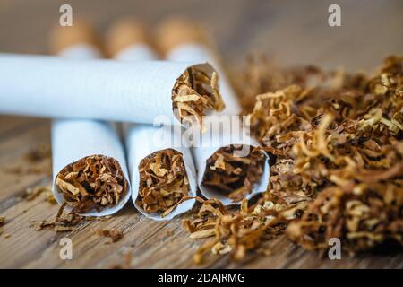 Schneiden Sie Tabakblätter und handgefertigte Zigaretten auf einem hölzernen Hintergrund Stockfoto