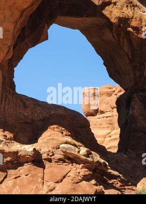 Die Lücke zwischen einem der Bögen von Double Arch, im Archers Nationalpark, Utah, mit der Silhouette einer Person, die ein Handy-Foto macht. Stockfoto
