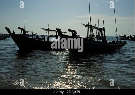 Silhouetten der birmanischen Fischer bereit ihre Fischerboote für eine Nächte Angeln als die Sonne untergeht auf Ngapali Strand Myanmar Stockfoto