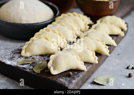 Knödel mit Kartoffeln mit Kräutern auf einem blauen Hintergrund. Wareniki, vareniki, Pierogi, pyrohy-Knödel mit Füllung. Stockfoto