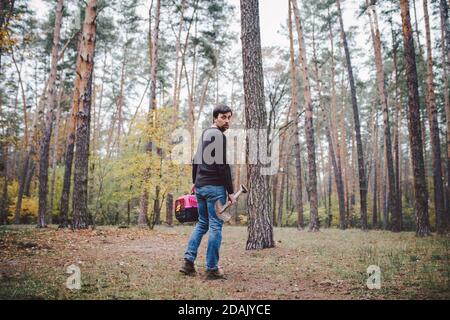Thema ist der Tod des Haustieres. Rückansicht des Mannes, der entlang Waldweg geht und Schaufel in einer Hand zum Graben Grab trägt, und in anderen Transportbox mit Stockfoto