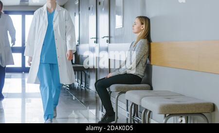 Viel Befahrene Krankenhausflure. Medizinisches Personal, Ärzte, Krankenschwestern, Chirurgen gehen, Patientin wartet an der Reihe. Moderne Medizinische Einrichtung. Stockfoto