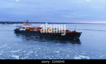 Luftaufnahme des Frachtschiffes, das durch das Meer bewegt. Im Hintergrund Winterlandschaft. Stockfoto