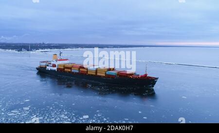 Luftaufnahme des Frachtschiffes, das durch das Meer bewegt. Im Hintergrund Winterlandschaft. Stockfoto