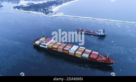 Luftaufnahme des Frachtschiffes, das durch das Meer bewegt. Im Hintergrund Winterlandschaft. Stockfoto