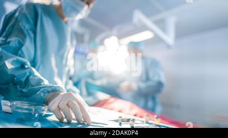 Nahaufnahme im Operationssaal des OP-Tisches mit Instrumenten nimmt der Assistent während der Operation Instrumente für Chirurgen auf. Chirurgie in Stockfoto