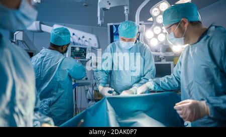 Vielfältiges Team von professionellen Chirurgen, Assistenten und Krankenschwestern, die invasive Chirurgie an einem Patienten im Operationssaal des Krankenhauses durchführen. Echt Modern Stockfoto
