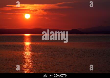 Isle of Arran, Schottland, Großbritannien. Sonnenuntergang über der Insel vom Strand in Ayr. Bekannt als der schlafende Riese aufgrund seiner Umrisse, besonders von der Ayrshire Coast aus gesehen. Stockfoto