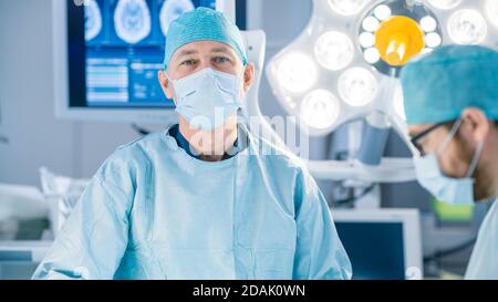 Porträtaufnahme im Operationssaal, von einem Chirurgen, der während der Operation in die Kamera schaut. Professionelle Ärzte, Die Chirurgie Durchführen. Stockfoto