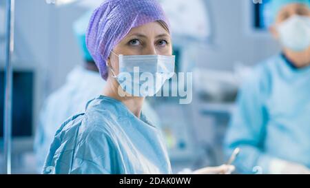 Porträtaufnahme einer Krankenschwester, die während der Operation im Operationssaal in die Kamera schaut. Professionelle Ärzte, Die Chirurgie Durchführen. Stockfoto